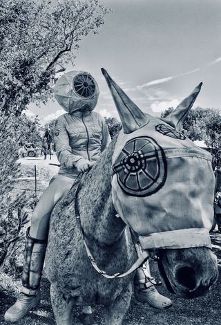 Ati Maier in a SpaceRider helmet on horseback, the horse wearing a fly mask painted with a wheel symbol.